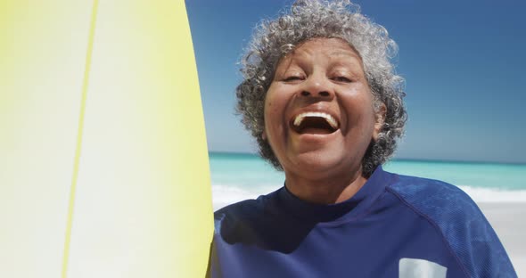 Senior woman with a surfboard smiling alt