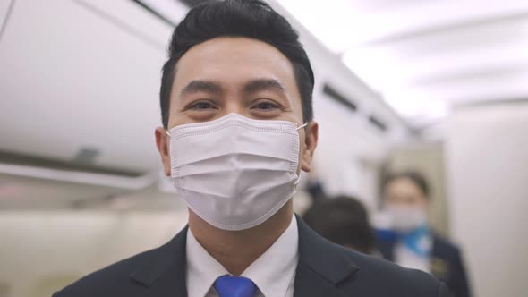 Asian male steward wearing medical face mask to prevent Coronavirus on airplane