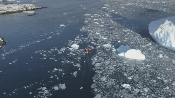 Polar Explorers in Motor Boat Sail Between Icebergs. Dangerous - People Afraid alt