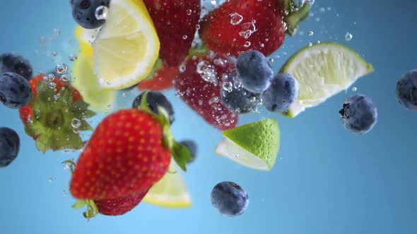 Super slow motion shot of fruit falling into the water with splashing. Blue background.