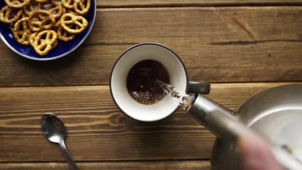 Tea Being Poured Into Cup From Kettle alt