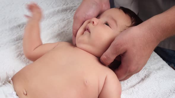 Male Doctor's Hands Massage the Baby. A Child Who Is Being Massaged Is Lying on the Couch. The First