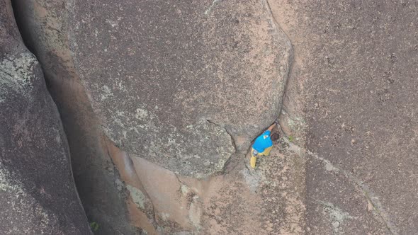 Top View of a Young Brave Man Climbing Solo on a Rock Crack