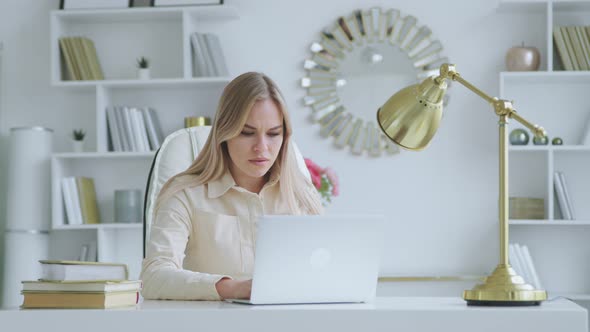 Unhappy young girl at work in the office. Serious woman typing on laptop at home alt
