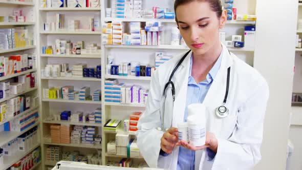 Smiling pharmacist showing medicine container in pharmacy alt