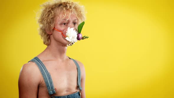 Young Redhead Queer Man in Nebulizer Mask Decorated with Flowers Standing on the Left at Yellow alt