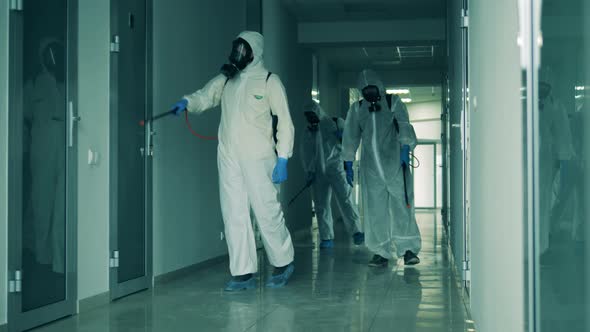Sanitation Workers Clean Hallway with Sprayers. alt