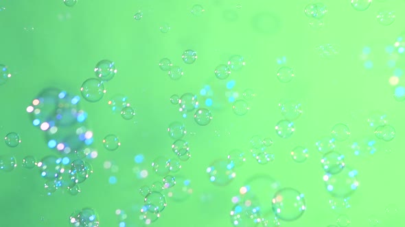 Blue and Clear Soap Bubbles on Light Green, Background, Slow Motion alt