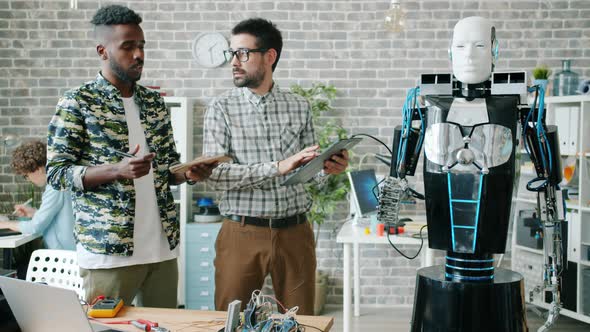 Scientists Testing Robot in Office Using Tablet Discussing Artificial Intelligence alt