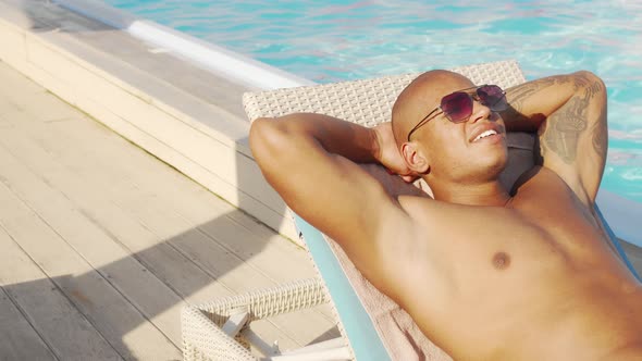 Sliding Shot of a Handsome African Man Sunbathing By the Pool
