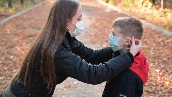 Woman Putting a Face Mask on Her Child Outdoors