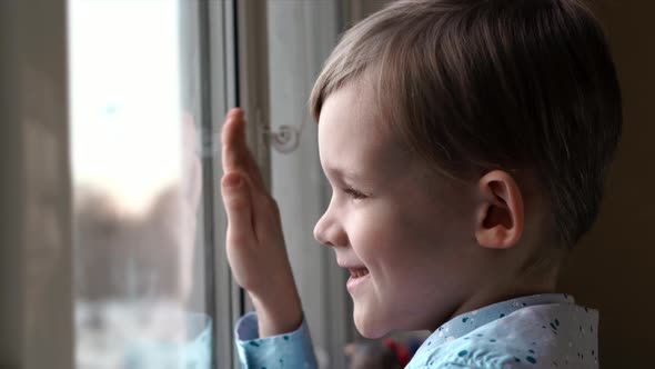 Happy Little Boy Waving His Hand and Smile in Window alt