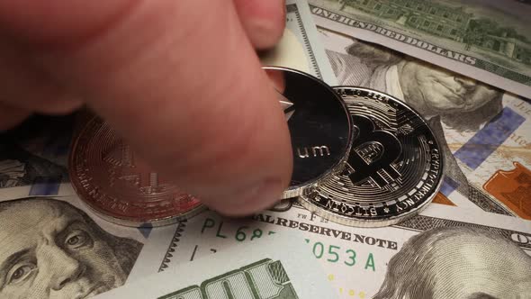 Ethereum coin placed on Bitcoin cryptocurrency stacked on 100 dollar bills alt