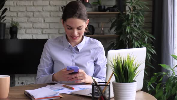 Funny euphoric young woman texting message on smartphone at home office. Excited girl receive read g alt