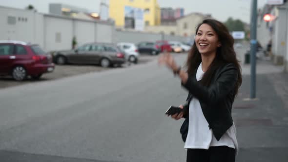 Young beautiful asian woman standing outdoor using smart phone and hitchhiking alt