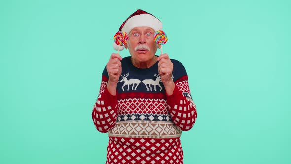 Grandfather in Christmas Sweater Holding Candy Striped Lollipops Hiding Behind Them Fooling Around alt