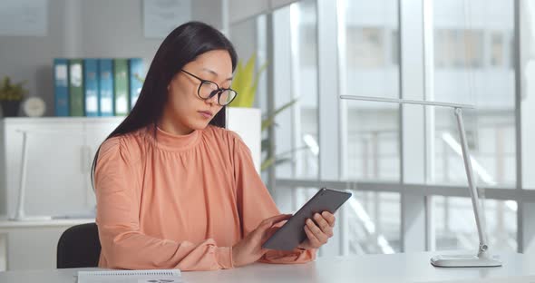 Portrait of Asian Businesswoman Working with Digital Tablet on Office Desk alt