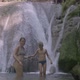 A Woman Gives Her Hand to a Child in the Background of a Waterfall - VideoHive Item for Sale