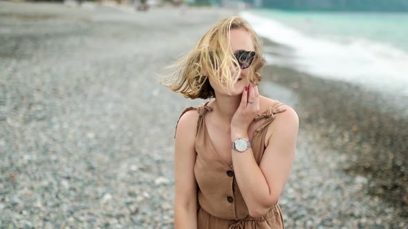 Attractive Cheerful Woman Walks By the Sea with Glasses