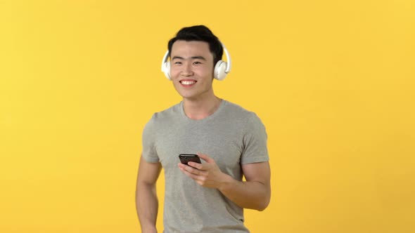 Asian man wearing headphones enjoyed listening to music from smartphone
