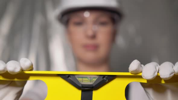 Woman Builder in Blue Overalls and White Hard Hat Helmet with Level