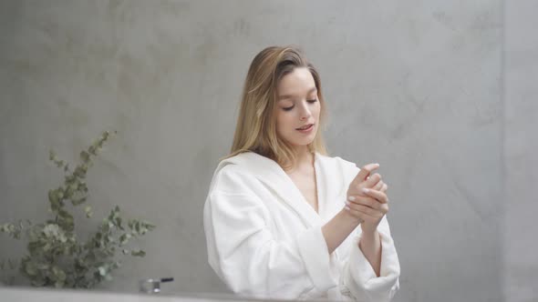 Goodlooking Woman in Bathrobe Looking at Mirror in the Morning