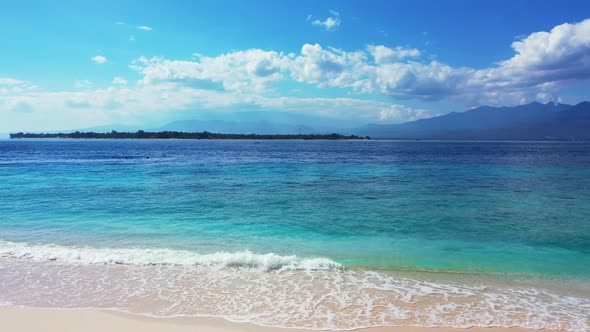 Daytime flying travel shot of a white paradise beach and blue sea background in 4K alt