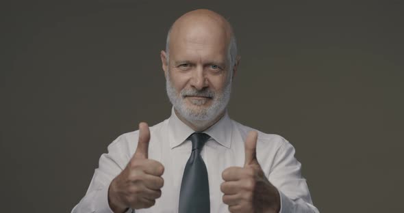 Confident middle-aged businessman smiling at camera and giving a thumbs up