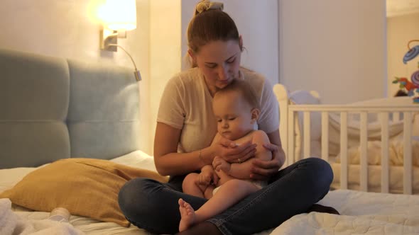 Worried Mother Holding Crying Baby Son and Measuring Him Temperature with Thermometer alt
