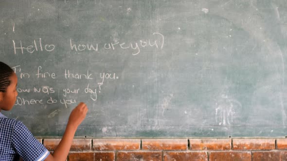 Schoolgirl writing on chalkboard in classroom 4k alt