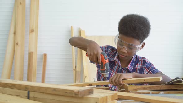 Little child with a drill in hands help dad assembling furniture shelf with power screwdriver tool alt