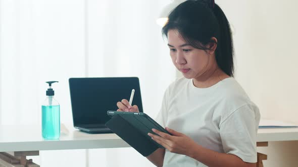 Asian woman using alcohol gel hand sanitizer wash hand before open tablet for protect coronavirus. alt