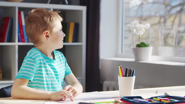 Boy is Doing  Homework at the Table. Cute Child is Learning at Home. alt