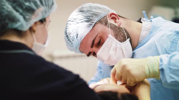 a man surgeon performs face and hands surgery close-up alt