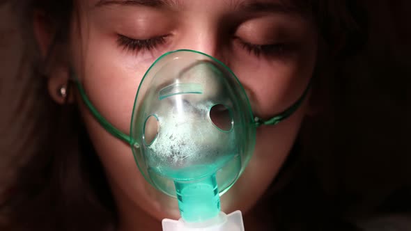 Young girl breathes medicine through inhaler apparatus