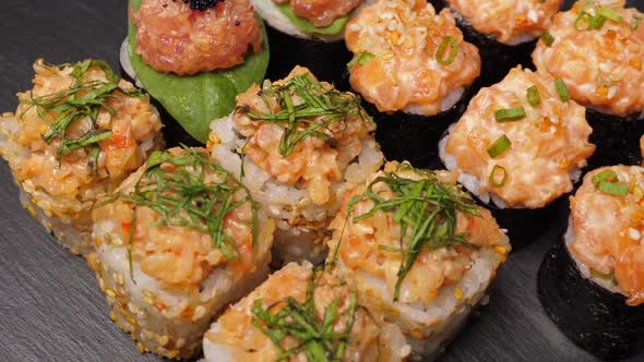 Sushi Rolls Set Rotating on Black Slate Board alt