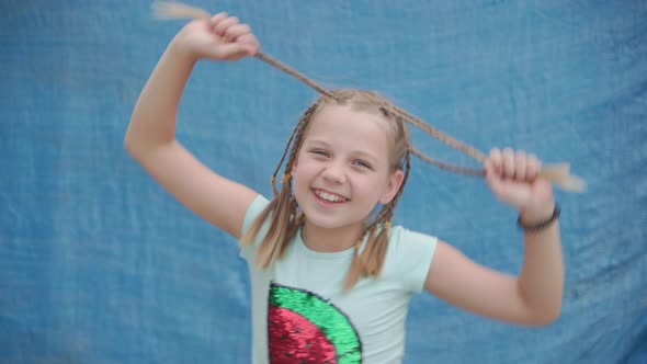 Playful Joyful Girl Shakes Her Head Holding Pigtails in Her Hands