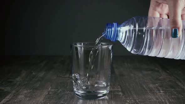 Female Hand Pours Water Into a Glass