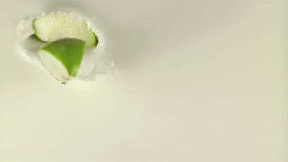 Super Slow Motion Pieces of Fresh Apple Fall Into the Milk with Splashes alt