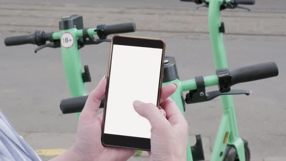 A woman orders electric scooters through her smartphone, ride sharing alt