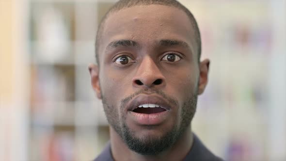 Close Up of Surprised Young African Man Looking at the Camera alt