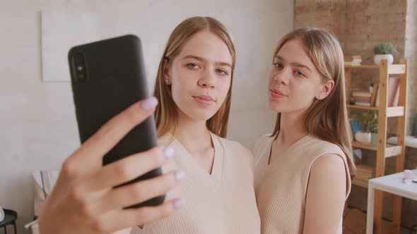 Laughing Twin Sisters Taking Selfie on Mobile Phone alt