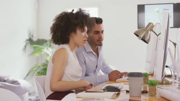 Two colleagues working on computer in creative office alt