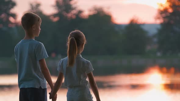 Happy Siblings Standing Together Holding Hands in Summer Park alt