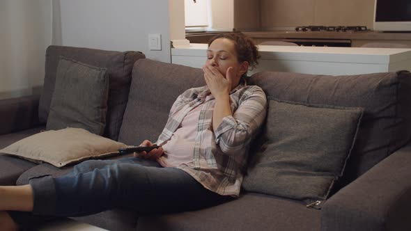 Moving Shot of Weary Adult Woman Yawning Watching TV Set at Home alt