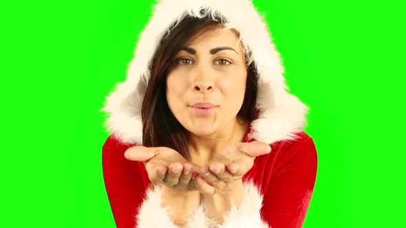 Pretty brunette in santa hat blowing over hands alt