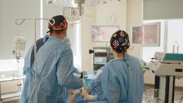 Back View of Surgeons Team Looks at Monitors While Preforming Operation in alt