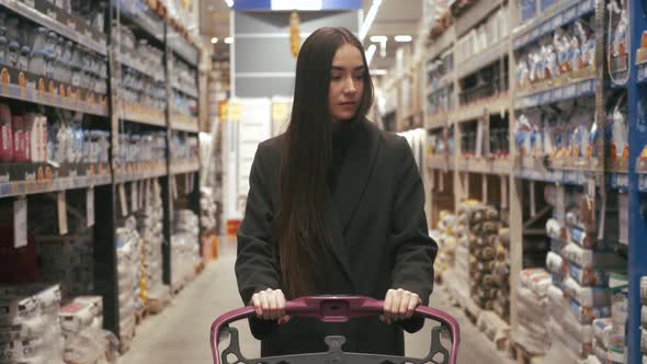 Woman choosing some stuff in hardware store. Pushing shopping cart buying materials in house improve