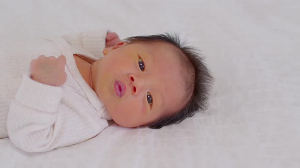 Top view happy newborn baby lying sleeps on a white blanket comfortable alt