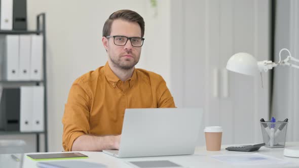 Young Man with Laptop Looking at the Camera  alt